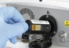 A person wearing a medical glove handles an electronic device.