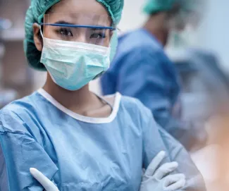 A healthcare works wears a PPE including a gown, mask, gloves and face shield.